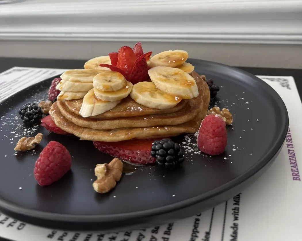 A stack of pancakes with bananas and berries at Mia's Cafe
